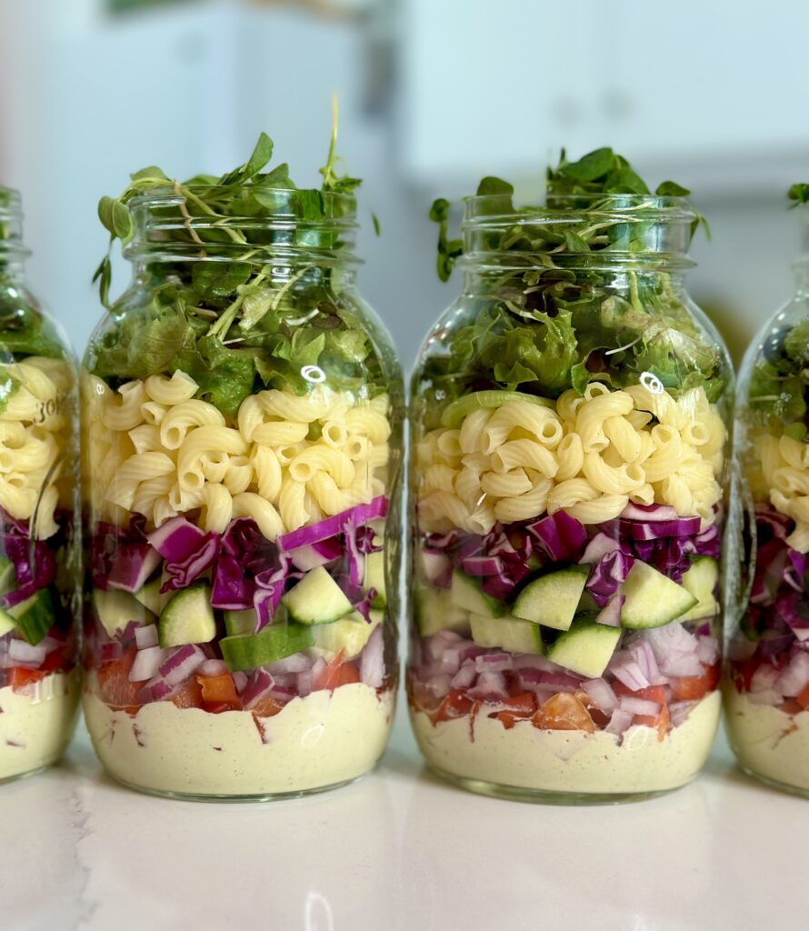 mason jars layered with creamy dill dressing, veggies, noodles and lettuce