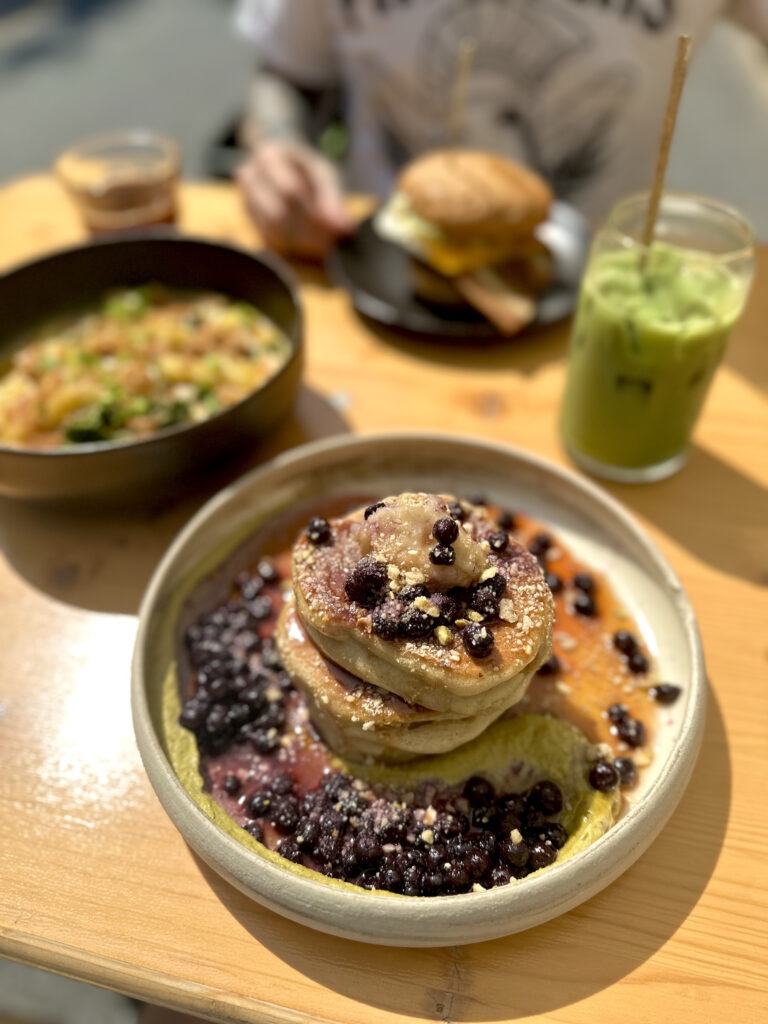 Archway vegan food pancakes with berries around it, pistachio sauce spread out and pancakes on top.