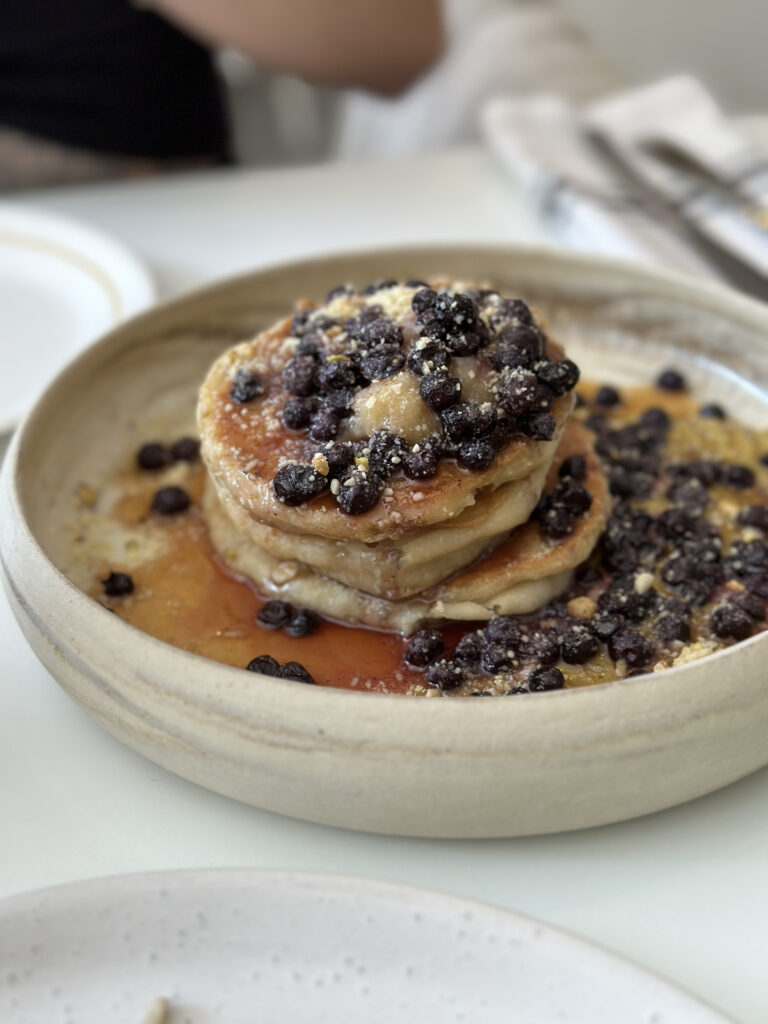 vegan baklava pancakes with berries on top and surrounding pancakes. 