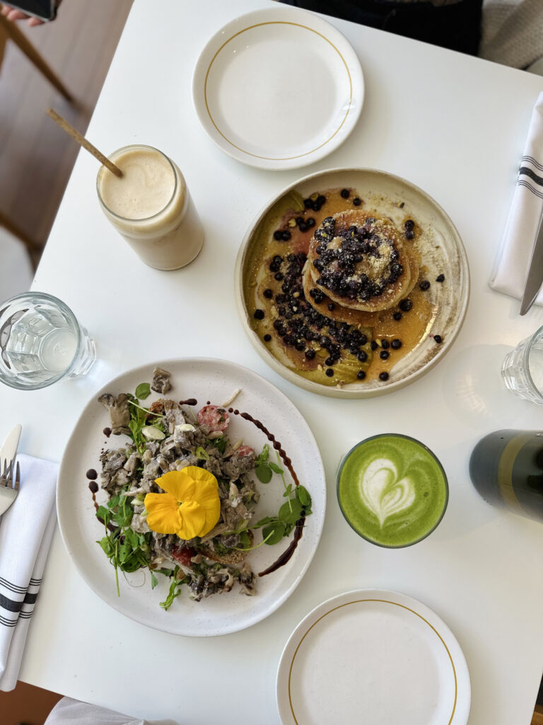 archway table set up with matcha, iced coffee, mushroom toast and pancakes.