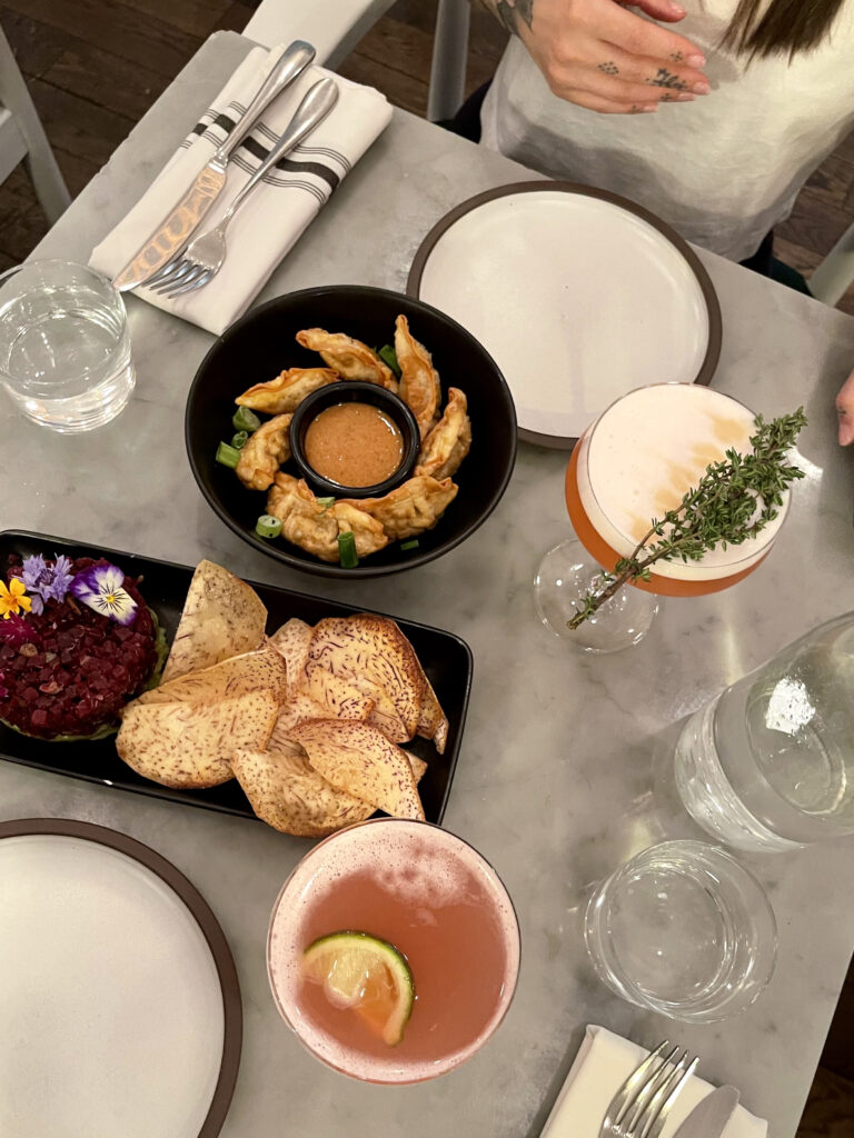 table view of meal from lov with beet tartare and dumplings with 2 mocktails 