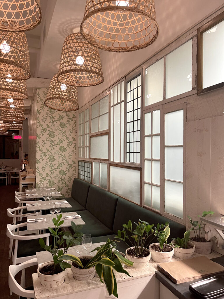 lov restaurant's beautiful indoor aesthetic with plants, white walls and tables with rattan basket lights.