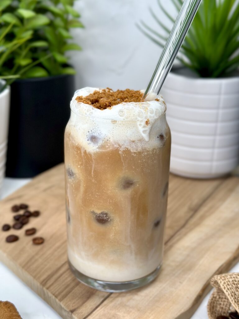 salted caramel cookie butter latte with crushed Lotus Biscoff cookies on top. cold foam pouring over cup.