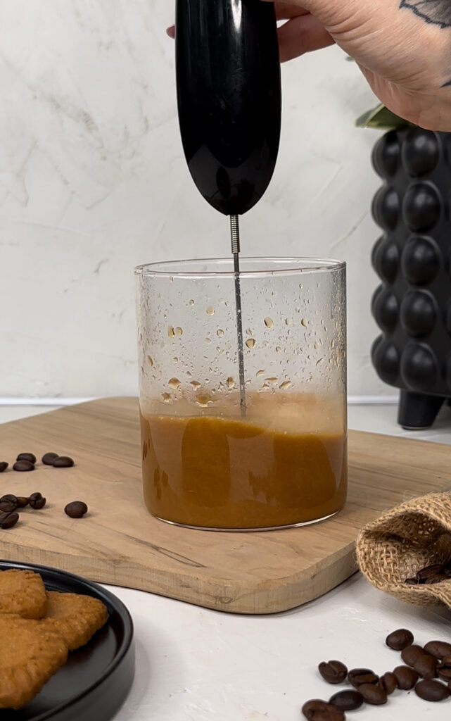 using handheld frother to mix cookie butter and coffee