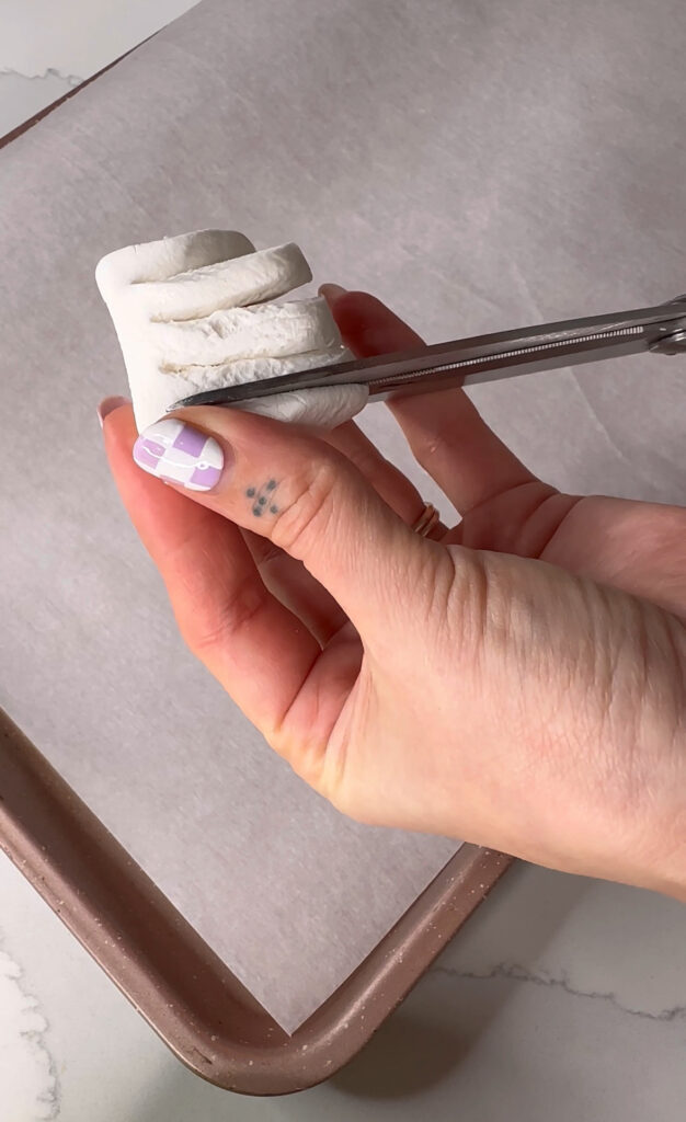 picture of woman holding marshmallow, making 4 cuts with scissors