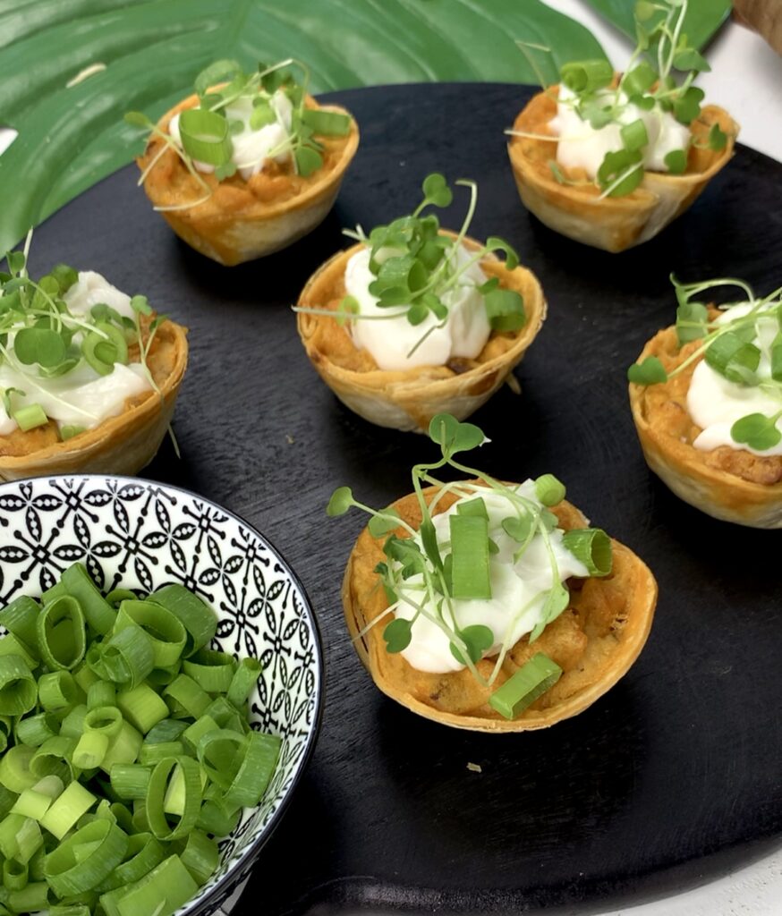 vegan buffalo chick'n bites topped with sour cream with green onions and microgreens