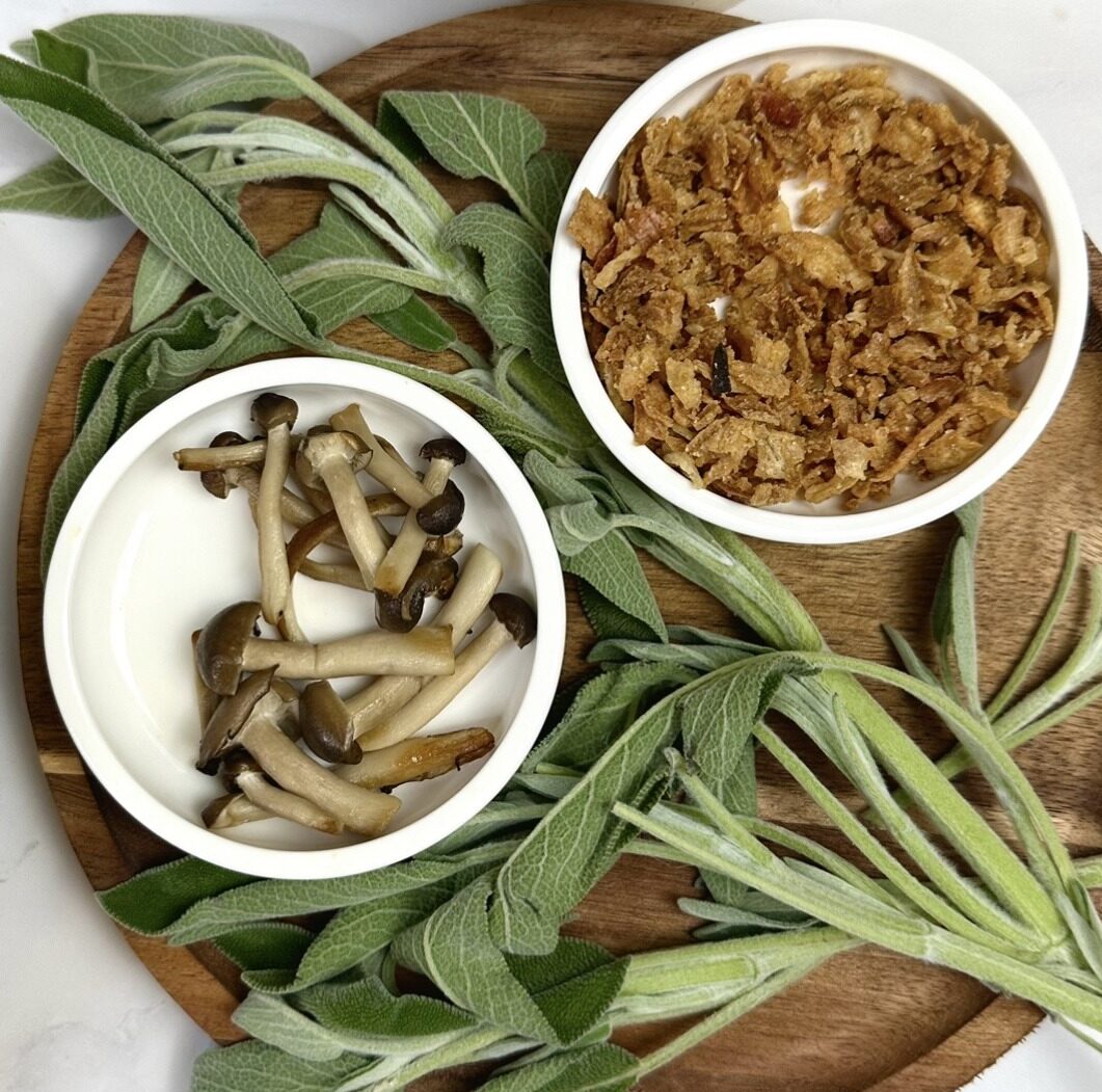 wooden tray of toppings such as mushrooms, crispy onions and sage