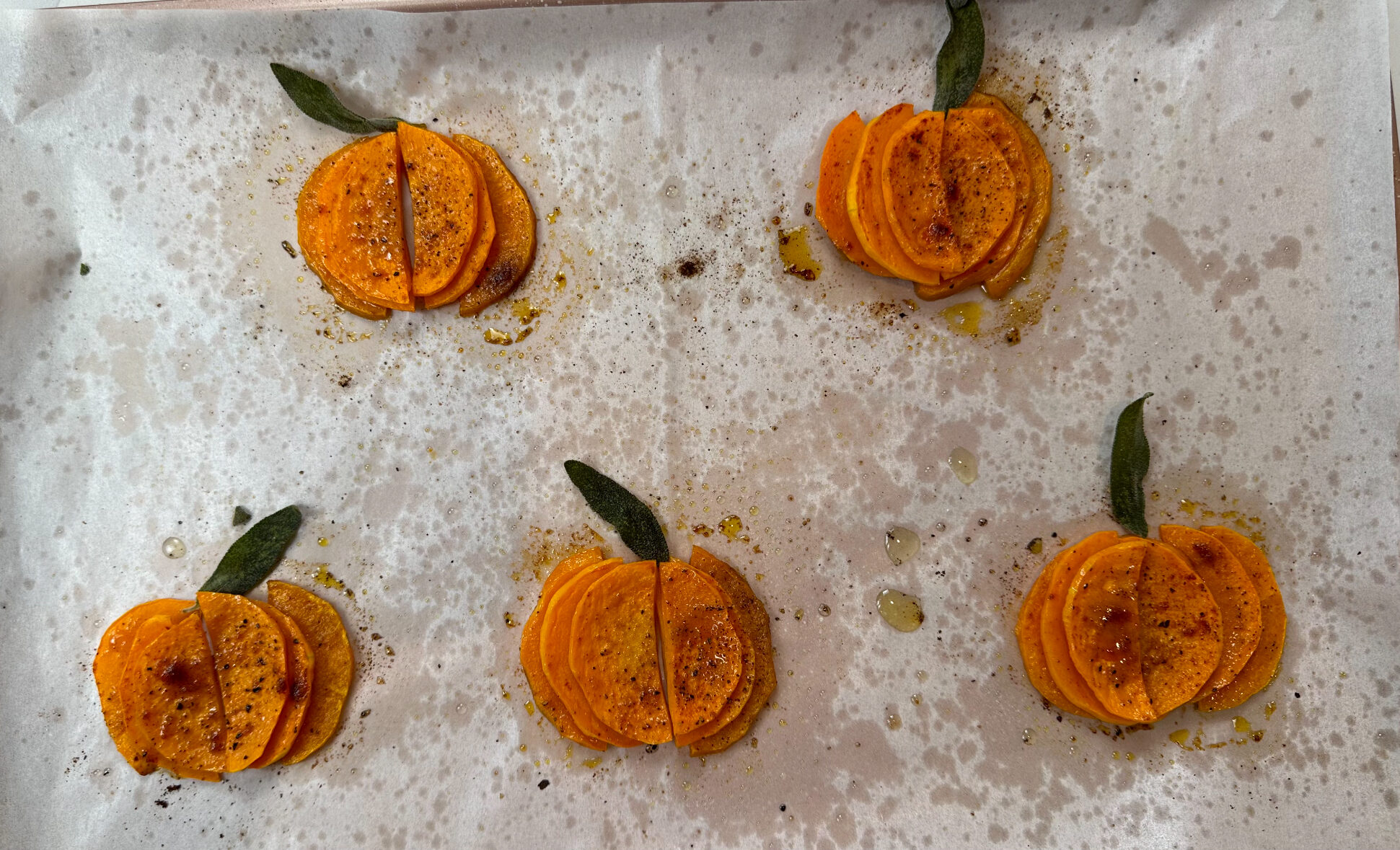 butternut squash pumpkins on a baking sheet with sage leaf stems 