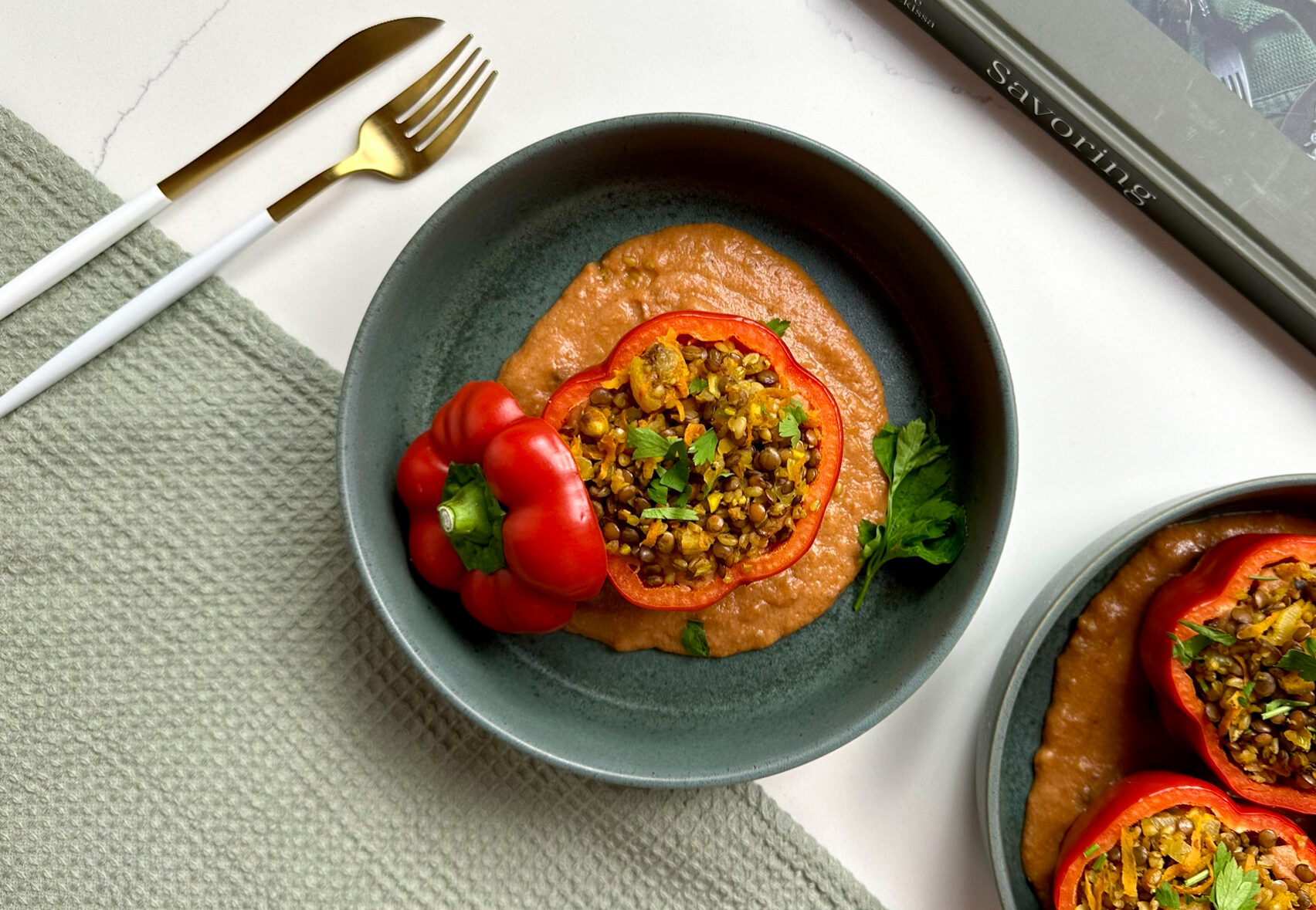 Photo of Moroccan Inspired Stuffed Bell Peppers sitting on a plate with tomato béchamel spread on the bottom. 