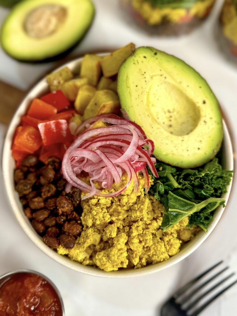 beautiful bowl with black beans, tofu scramble, red peppers, potatoes, kale, pickled red onions and avocado.