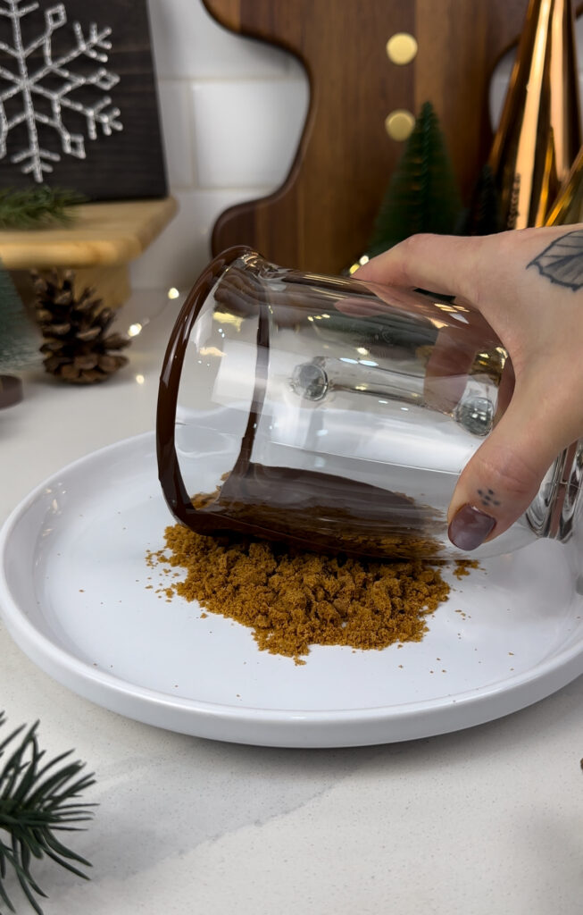 adding crushed biscoff cookie crumbs to the some melted chocolate on the rim of the mug.