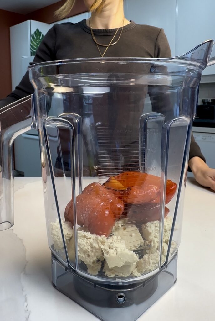 adding roasted red pepper, cherry tomatoes, garlic and seasonings to blender container.