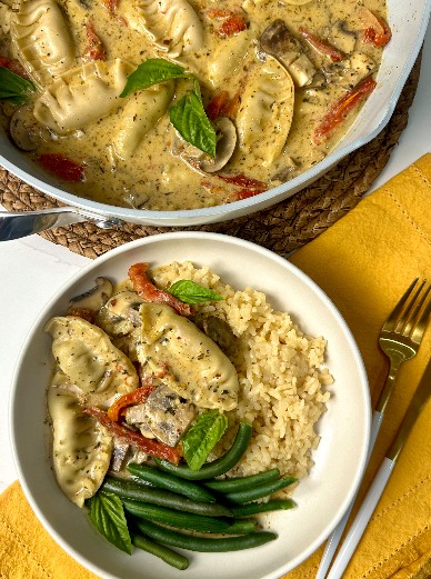 A skillet with Marry Me Dumplings next to a bowl, rice, and green beans