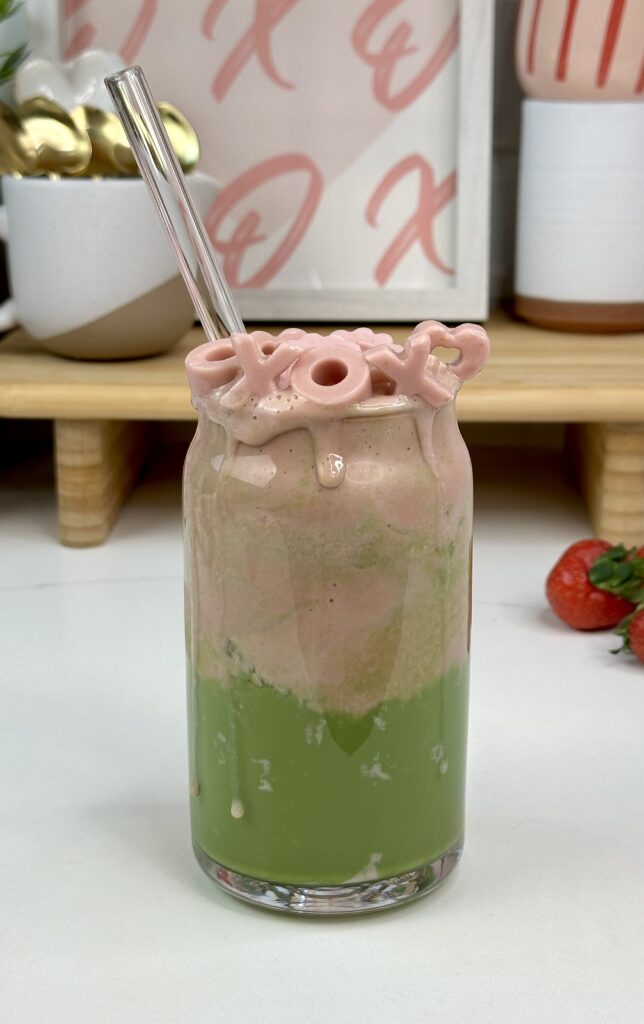 strawberry matcha latte with valentine themed strawberry ice cubes, strawberry cold foam and vibrant green matcha on the bottom