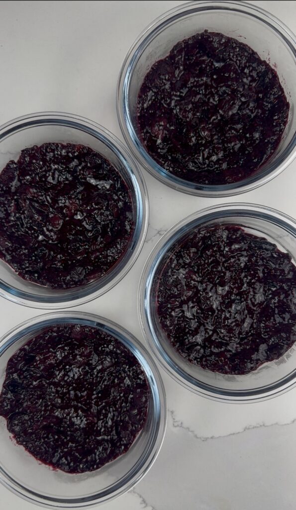 blueberry chia jam layered on the bottom of 4 meal prep containers