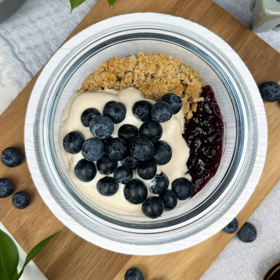 single bowl of blueberry shortcake meal prep with blueberry chia jam, shortcake crumble, vanilla yogurt, and fresh blueberries on top. 