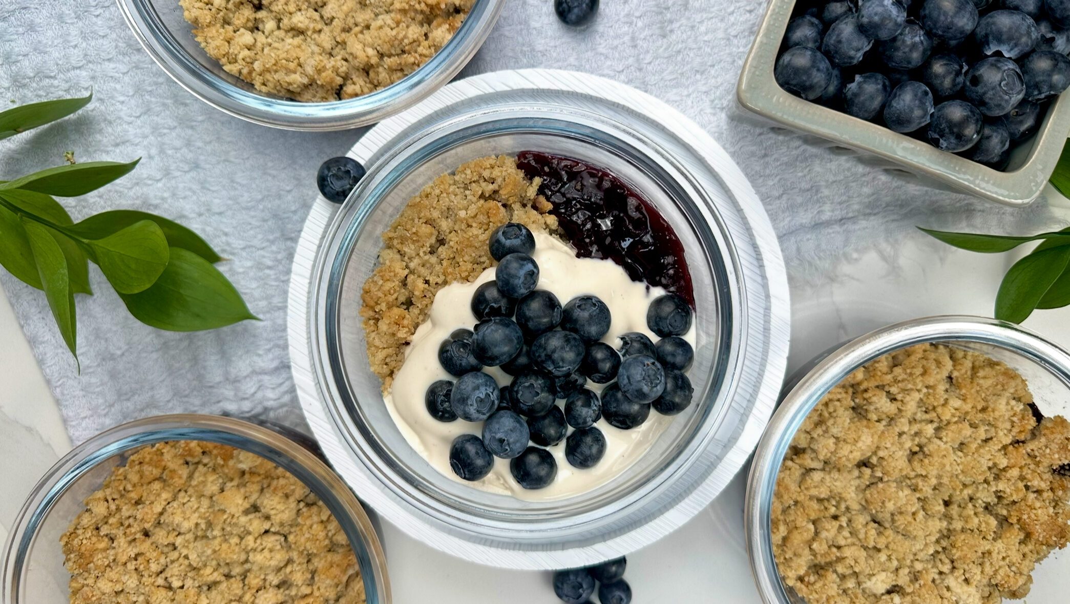 overhead shot of blueberry shortcake meal prep containers with vanilla yogurt and fresh blueberries on top. 