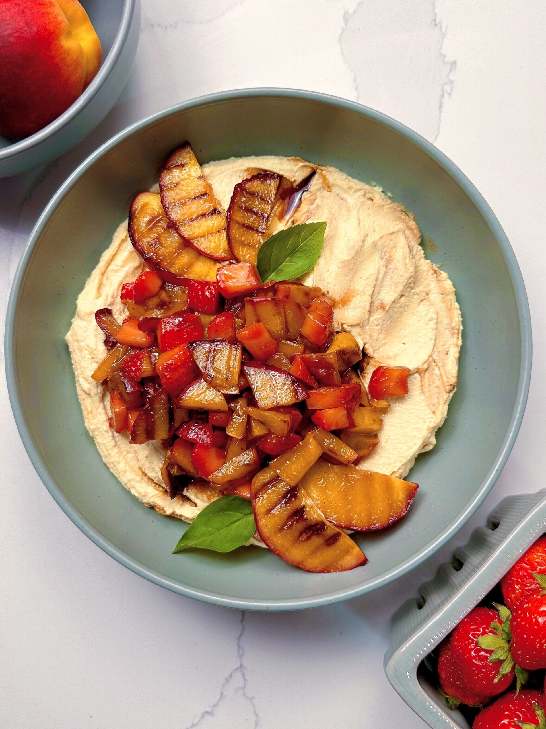 Bowl with whipped tofu ricotta on the bottom, and slices of strawberries and peaches. 