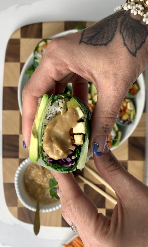 summer roll cut in half with peanut sauce drizzled on top