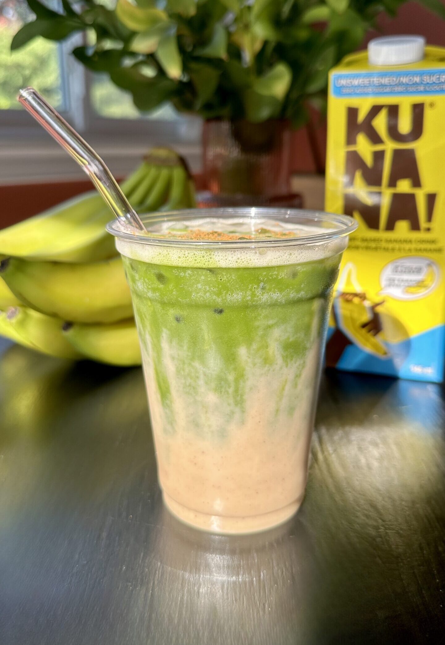 ice in cup with banana milk with matcha layer on top.