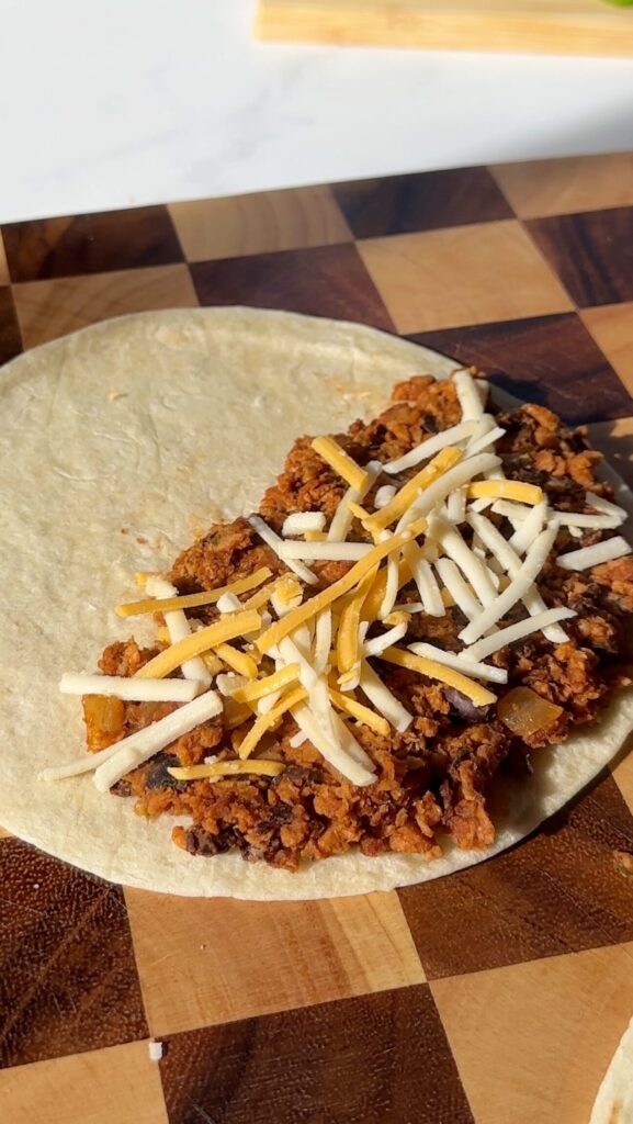 Spinkle vegan cheese on top of tortilla with black bean & TVP mixture.