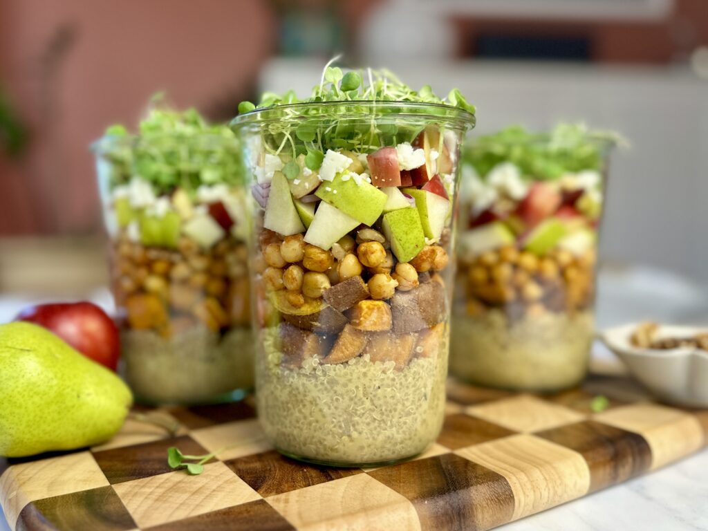 weck jar layered with dijon dressing, quinoa, roasted sweet potato, chickpeas, crisp chopped apples and pears, vegan feta, walnuts and arugula microgreens on top