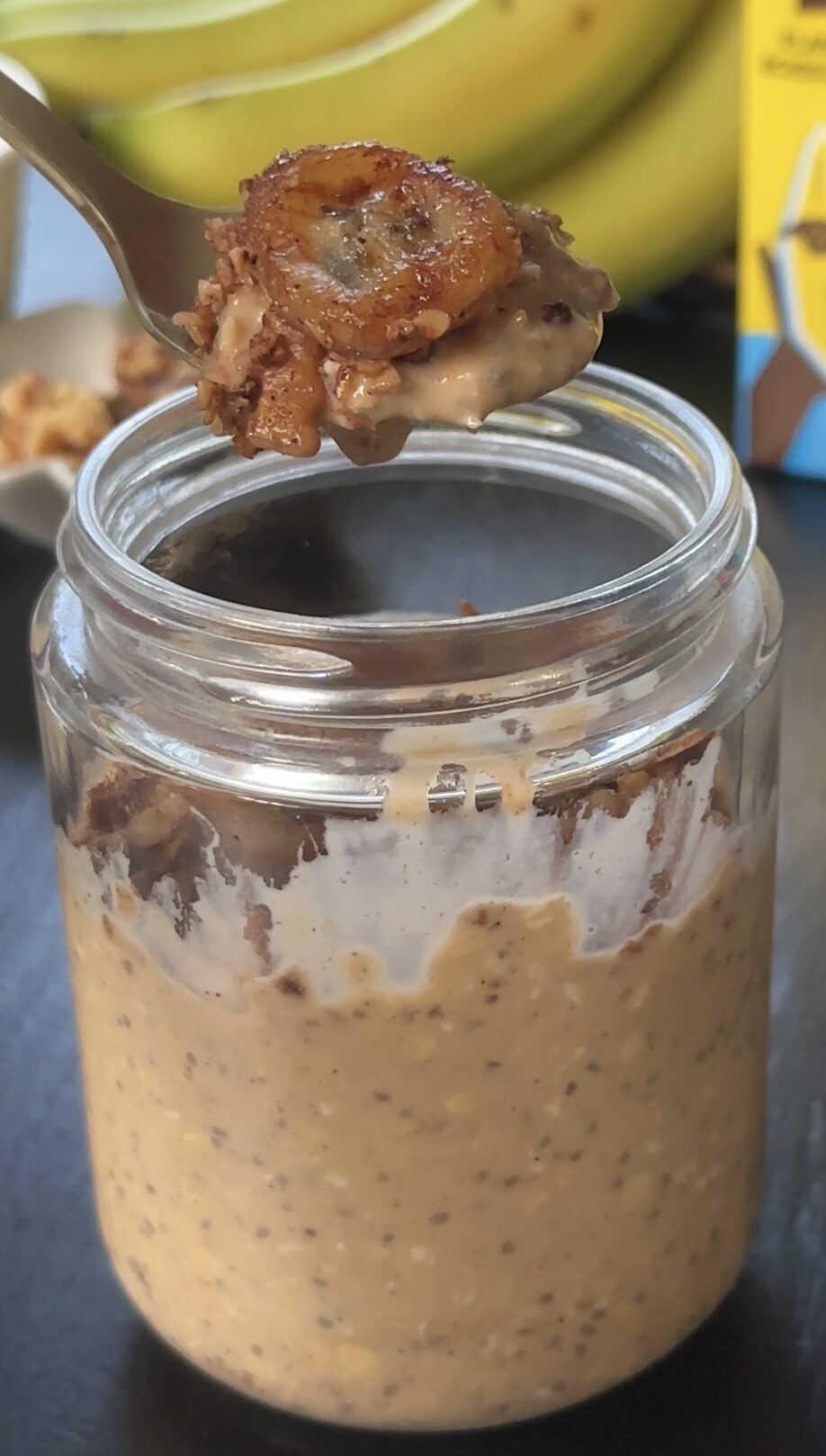 scooping out a spoonful of banana bread overnight oats from a meal prep jar.