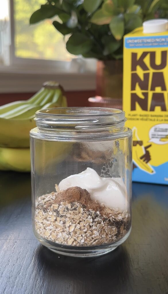breakfast prep jar filled with dried oats, chia seeds, cinnamon, nutmeg and vegan yogurt.