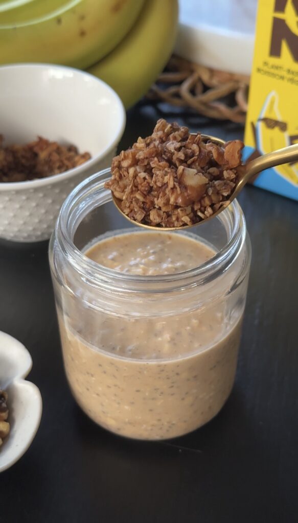 adding banana bread oat crumble on top of banana bread overnight oats mixture in jars.