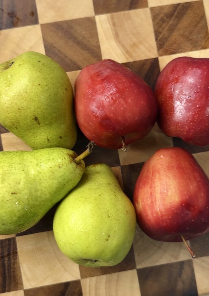 Fresh apples and pears on a checkered cutting board.
