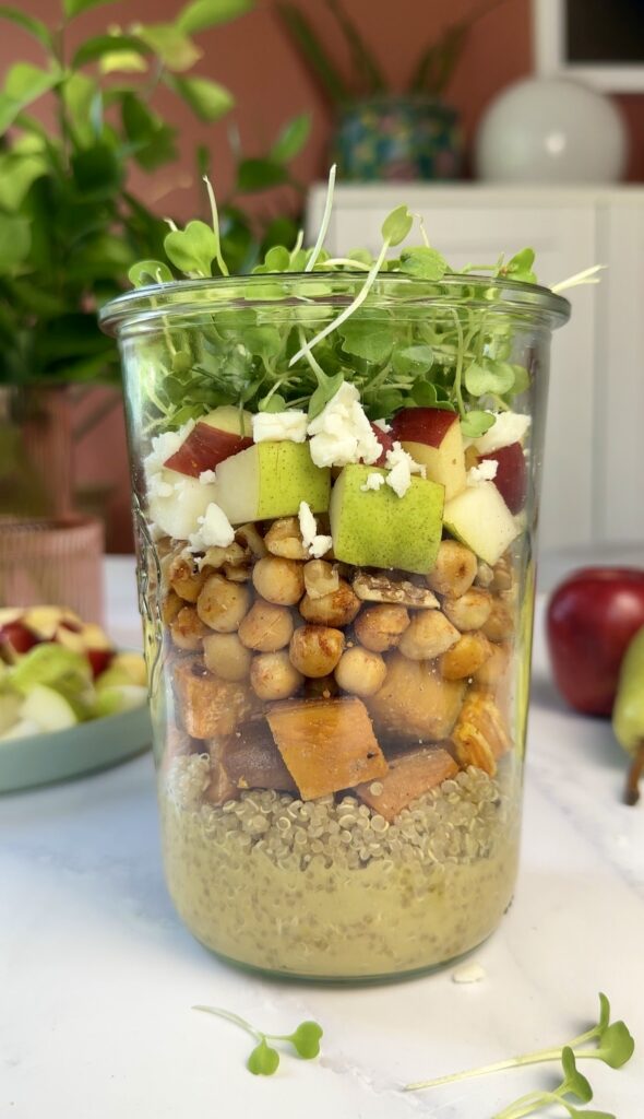 weck jar layered with dijon dressing, quinoa, roasted sweet potato, chickpeas, crisp chopped apples and pears, vegan feta, walnuts and arugula microgreens on top