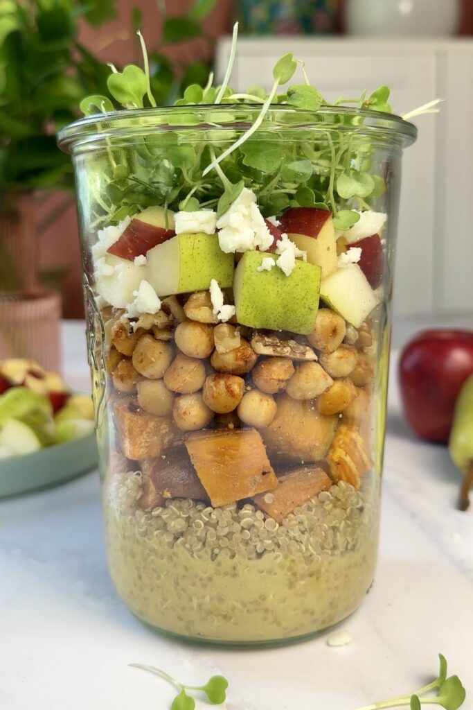 salad jar with layers of quinoa, sweet potato, chickpeas, pear, apples, vegan feta and microgreens.
