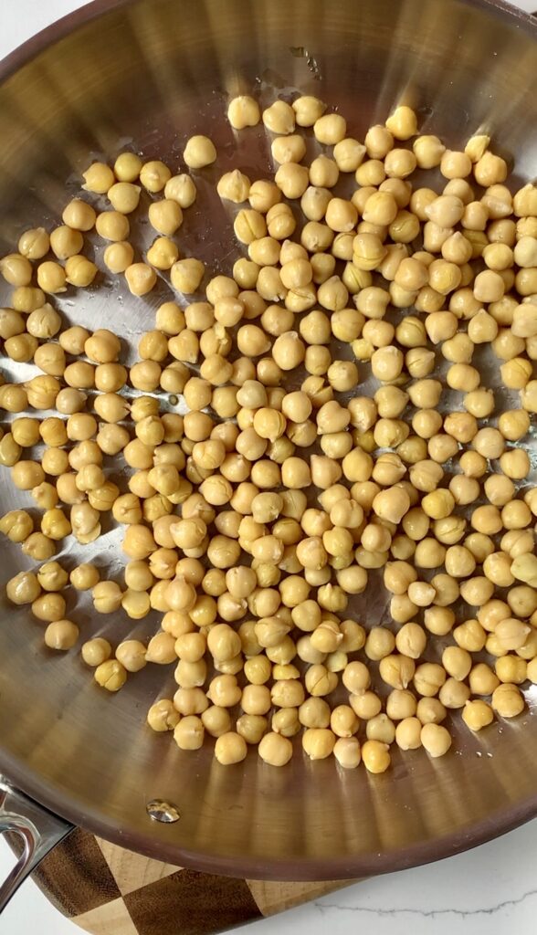 Stainless steel pan with olive oil and chickpeas.