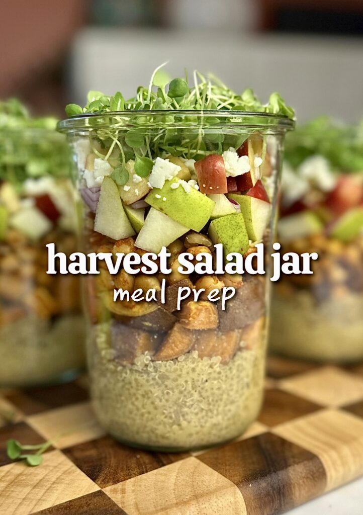 Glass salad jar with Dijon dressing on the bottom, followed by roasted sweet potato, chickpeas, diced apple and pear, vegan feta, chopped walnuts, and arugula microgreens on top.